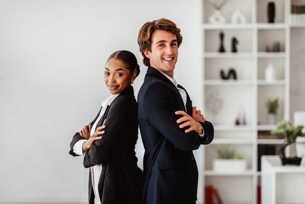 partnership. businessman and black businesswoman posing after successful deal, standing back to back and smiling