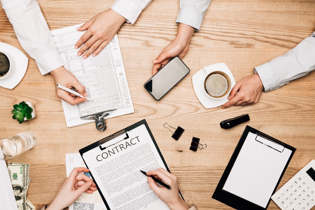 top view of business partners with contract, paperwork and coffee on wooden table