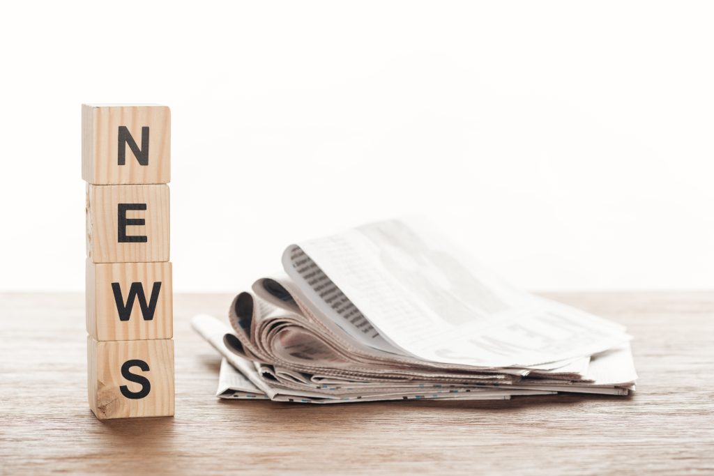 wooden cubes with word news and newspapers on wooden tabletop